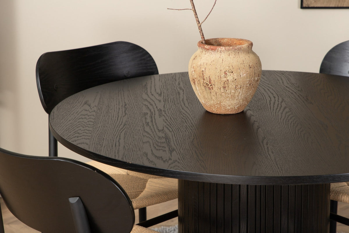 Rundes Esszimmerset Bianca mit Stuhl Polly: Tisch aus MDF und Furnier in Walnuss, vier schwarze Stühle mit Metallbeinen und Seilsitzen.