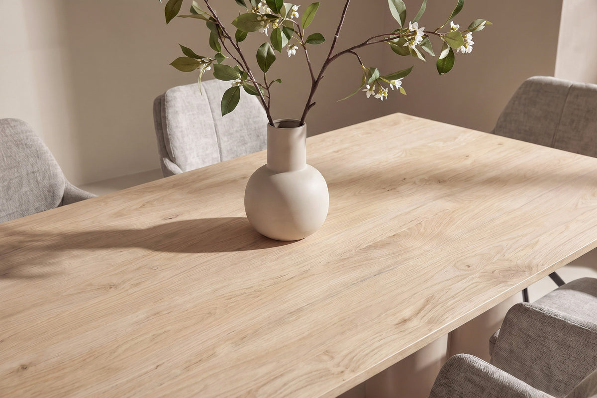 Rechteckiger Esstisch 210x100 cm mit Tischplatte in Whitewash aus MDF und Papierlaminat, dazu zwei gepolsterte Esszimmerstühle in Braun mit Metallbeinen.