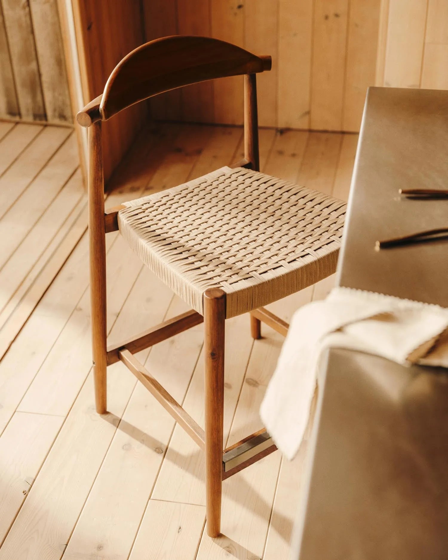 Der Nina Hocker aus Akazienholz mit nussbaumfarbenem Finish und beigem Seilgeflecht vereint Eleganz und Langlebigkeit.