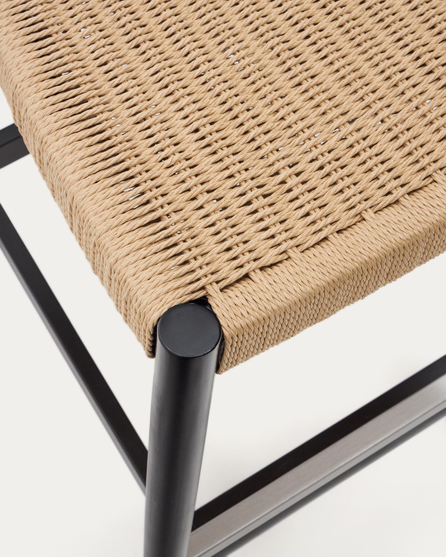 Entdecken Sie den Nina Hocker von Kave Home: Ein stilvolles Möbelstück aus massivem Akazienholz mit elegantem schwarzem Finish und beigem Seil, ideal für Ihren Außenbereich.