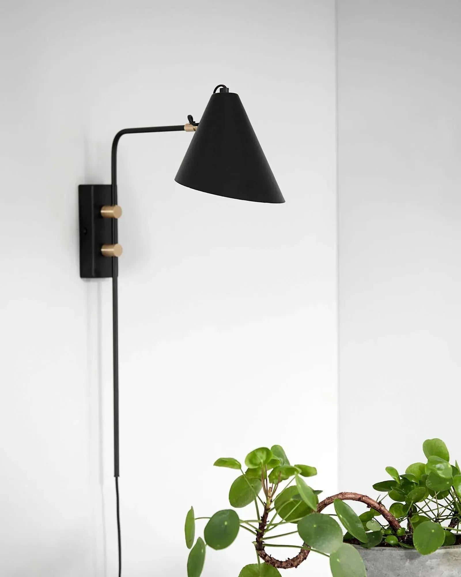 Die Wandleuchte Club von House Doctor vereint industriellen Charme mit skulpturalem Design. Flexibel einstellbar, aus schwarzem Eisen und goldenem Messing.