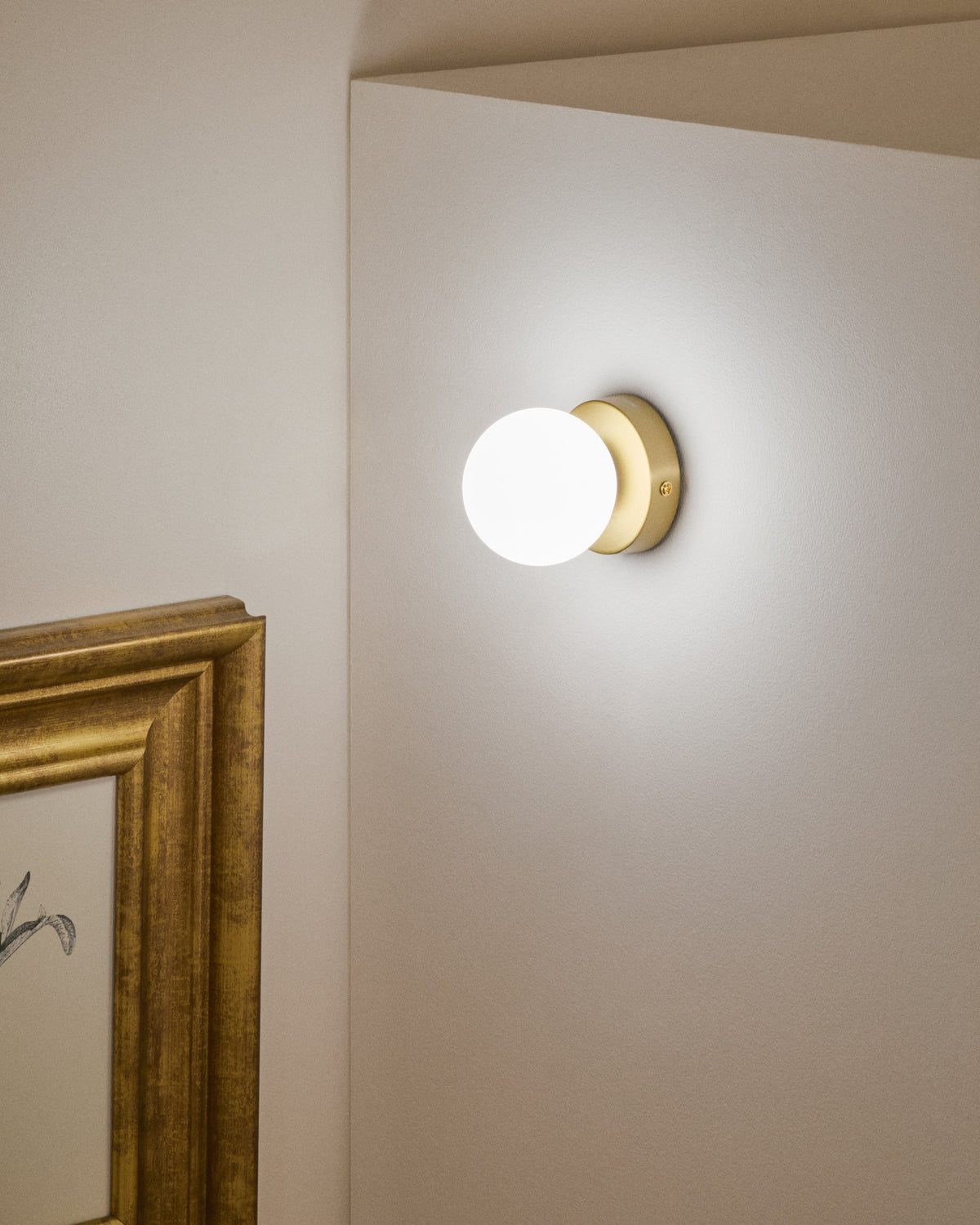 Wandleuchte Brisia aus Metall mit gebürstetem Messing-Finish und einer mattierten Glaskugel Ø 8 cm in Gold präsentiert im Onlineshop von KAQTU Design AG. Wandleuchte ist von Kave Home