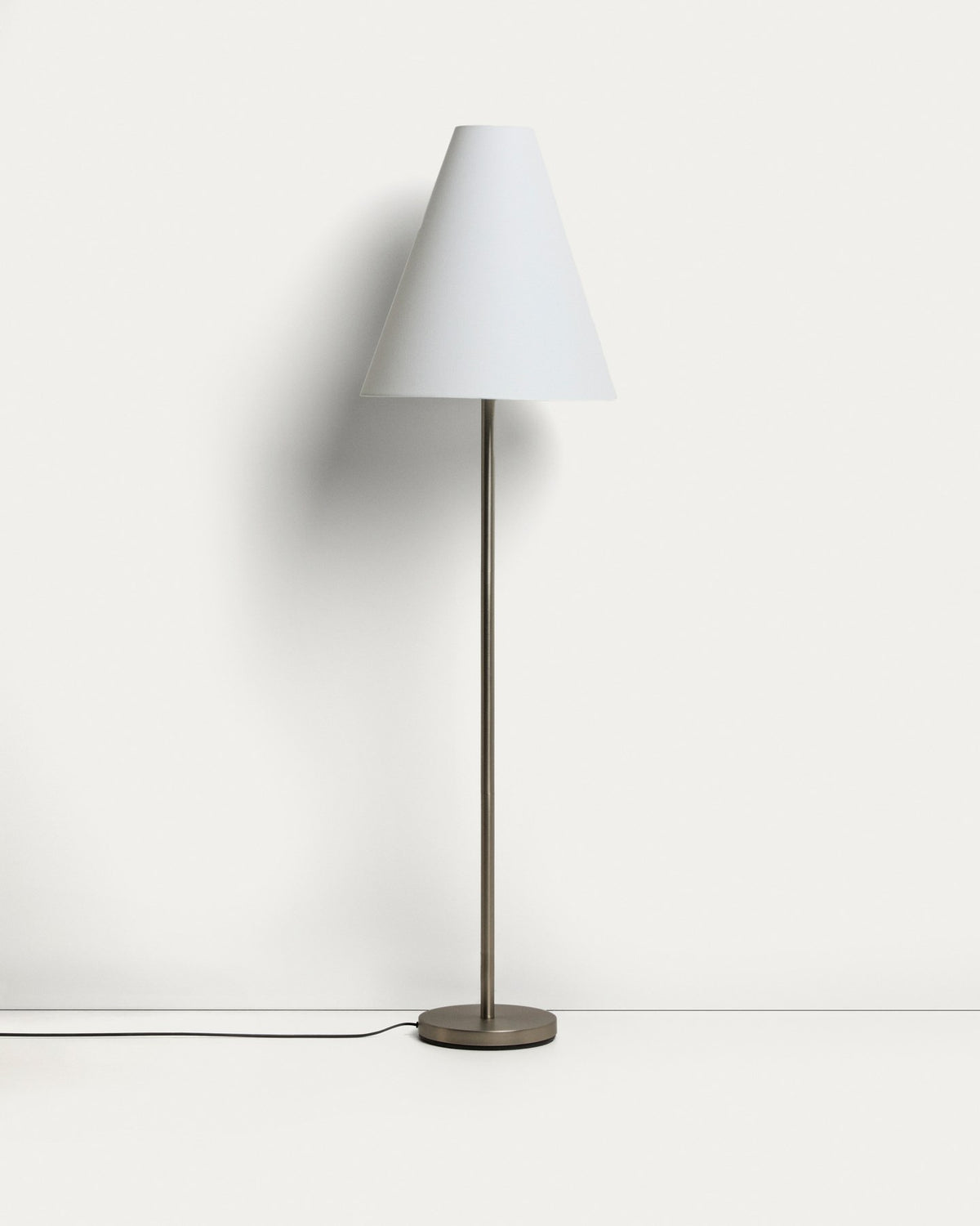 Stehlampe aus Metall mit silbernem, gebürstetem Finish und konischem Lampenschirm aus Baumwollstoff in gebrochenem Weiss, mit Stahlsockel.