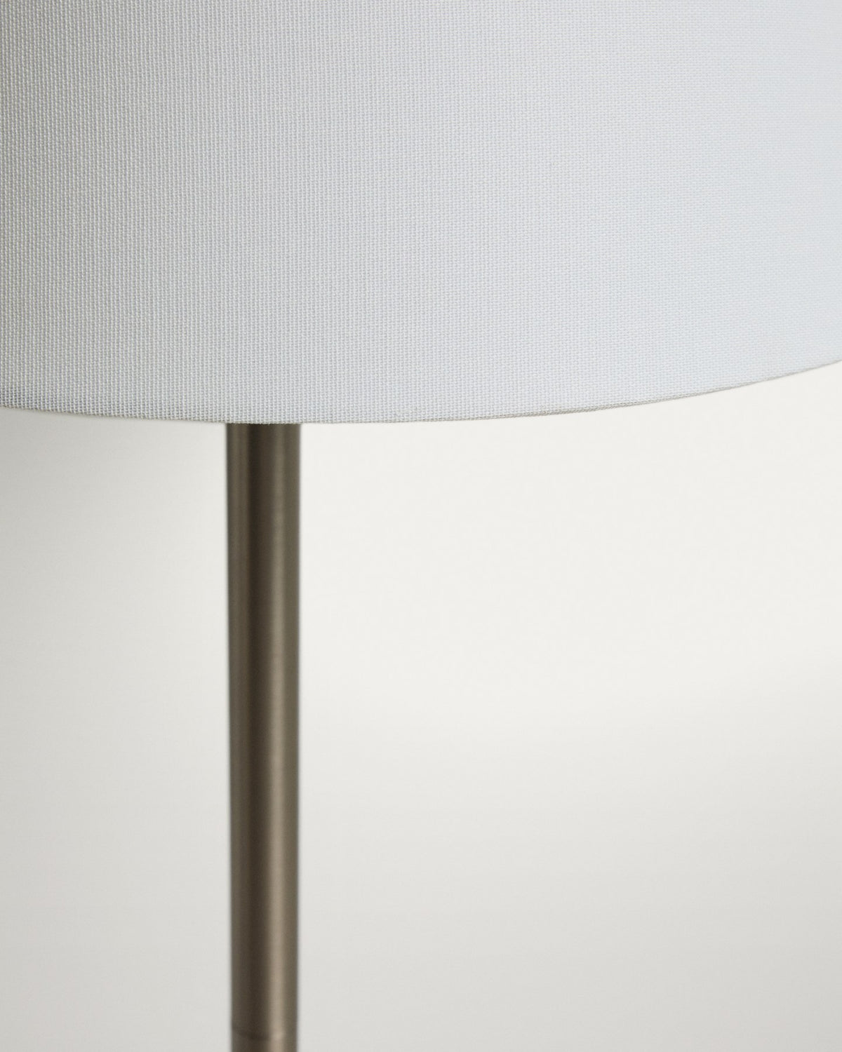 Stehlampe aus Metall mit silbernem, gebürstetem Finish und konischem Lampenschirm aus Baumwollstoff in gebrochenem Weiss, mit Stahlsockel.