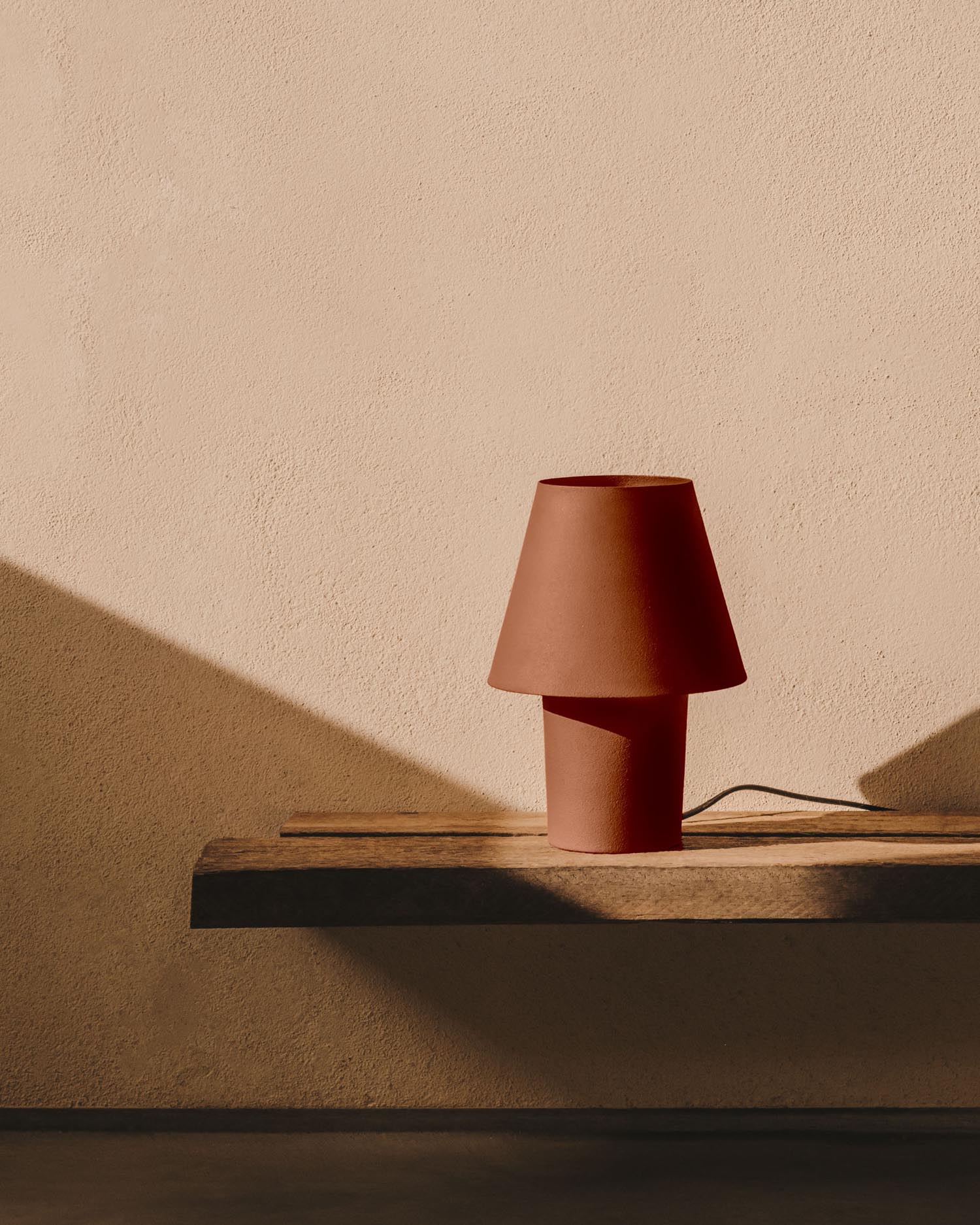 Die Canapost Tischlampe aus Metall in Terrakotta-Finish von Kave Home vereint modernes Design mit warmen Farbtönen.