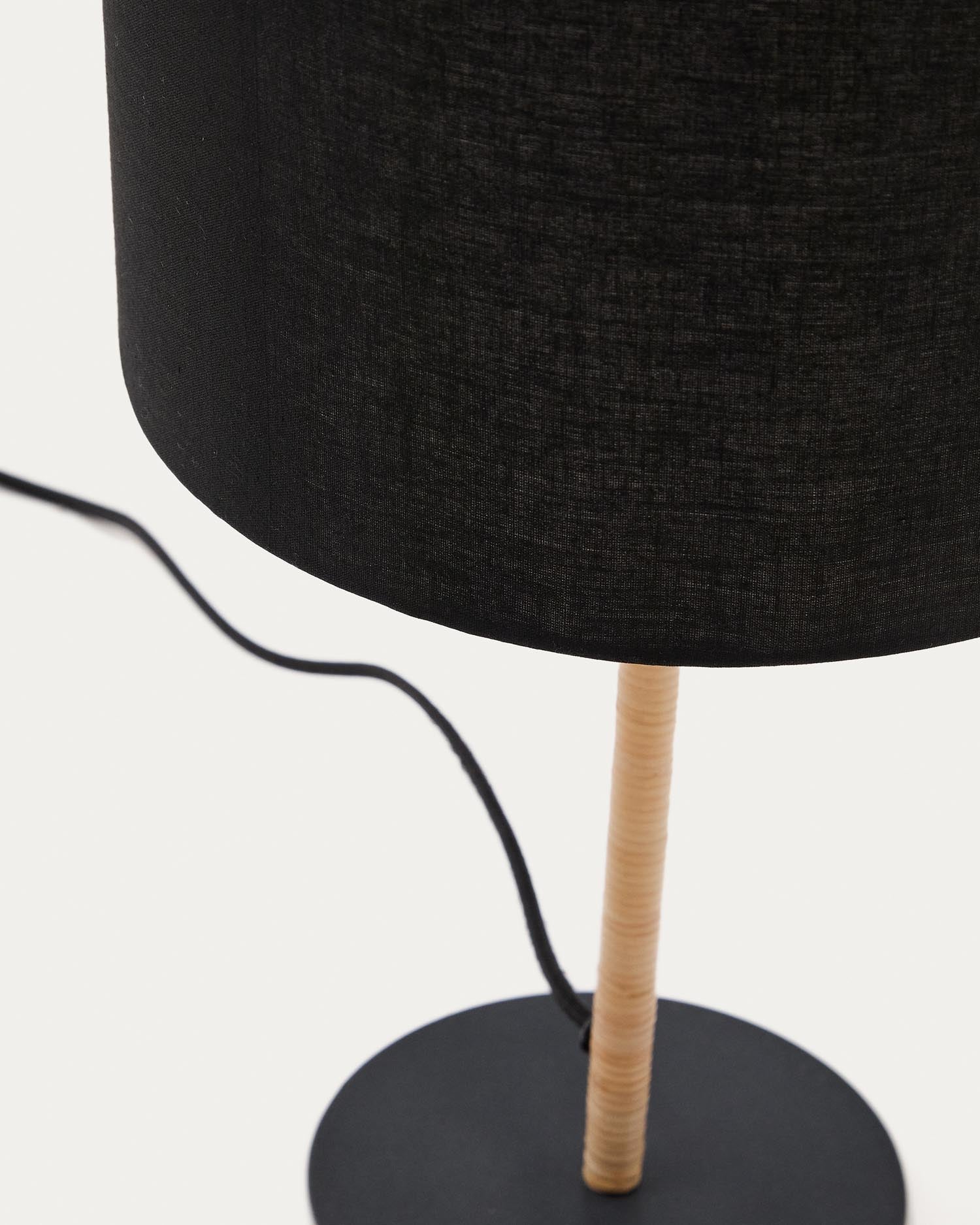 Die Pina Tischlampe kombiniert Metall, Rattan und einen schwarzen Baumwollschirm für stilvolle Beleuchtung.