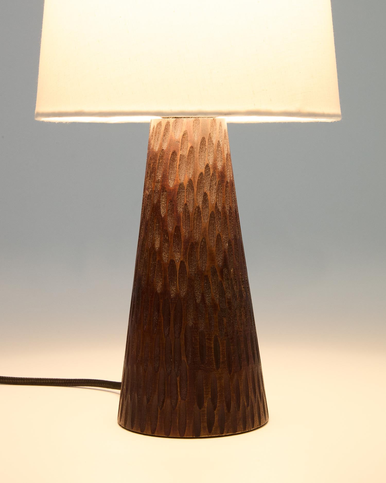 Die Tischleuchte Amire aus Holz mit dunklem Finish von Kave Home bietet stilvolle Beleuchtung für ein modernes Wohnambiente.