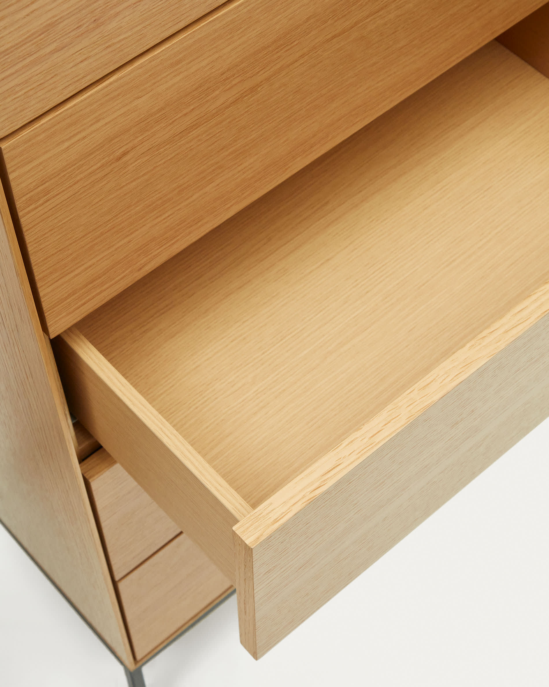 Die Vedrana Kommode kombiniert Eichenfurnier und schwarze Stahlbeine, bietet 5 Schubladen und misst 60 x 114 cm – stilvoll und funktional.