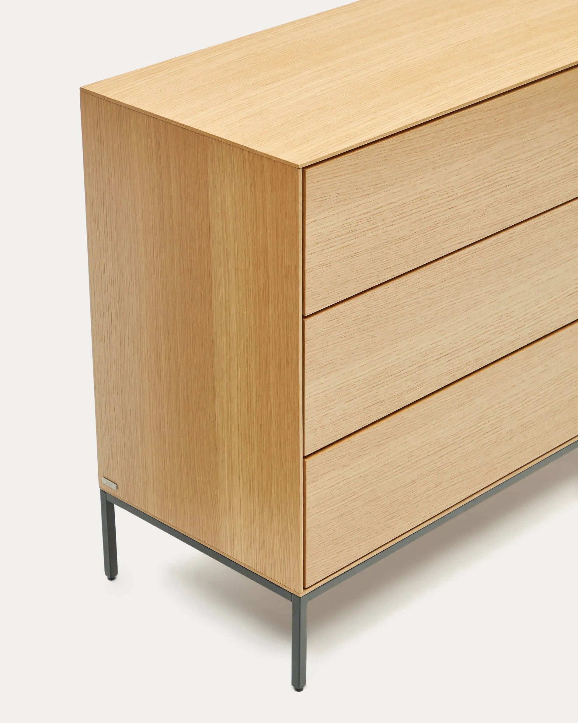 Die Vedrana Kommode aus Eichenfurnier mit schwarzen Stahlbeinen bietet 3 Schubladen und misst 110 x 75 cm. Modern und funktional.