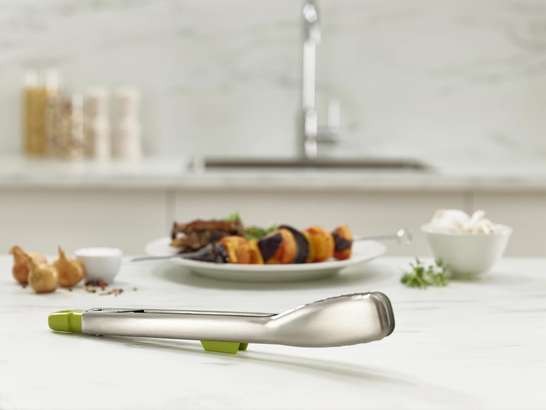 Elegante Edelstahlzange in frischem Grün, ideal für das Kochen und Servieren, mit cleveren integrierten Auflagen für zusätzlichen Komfort.