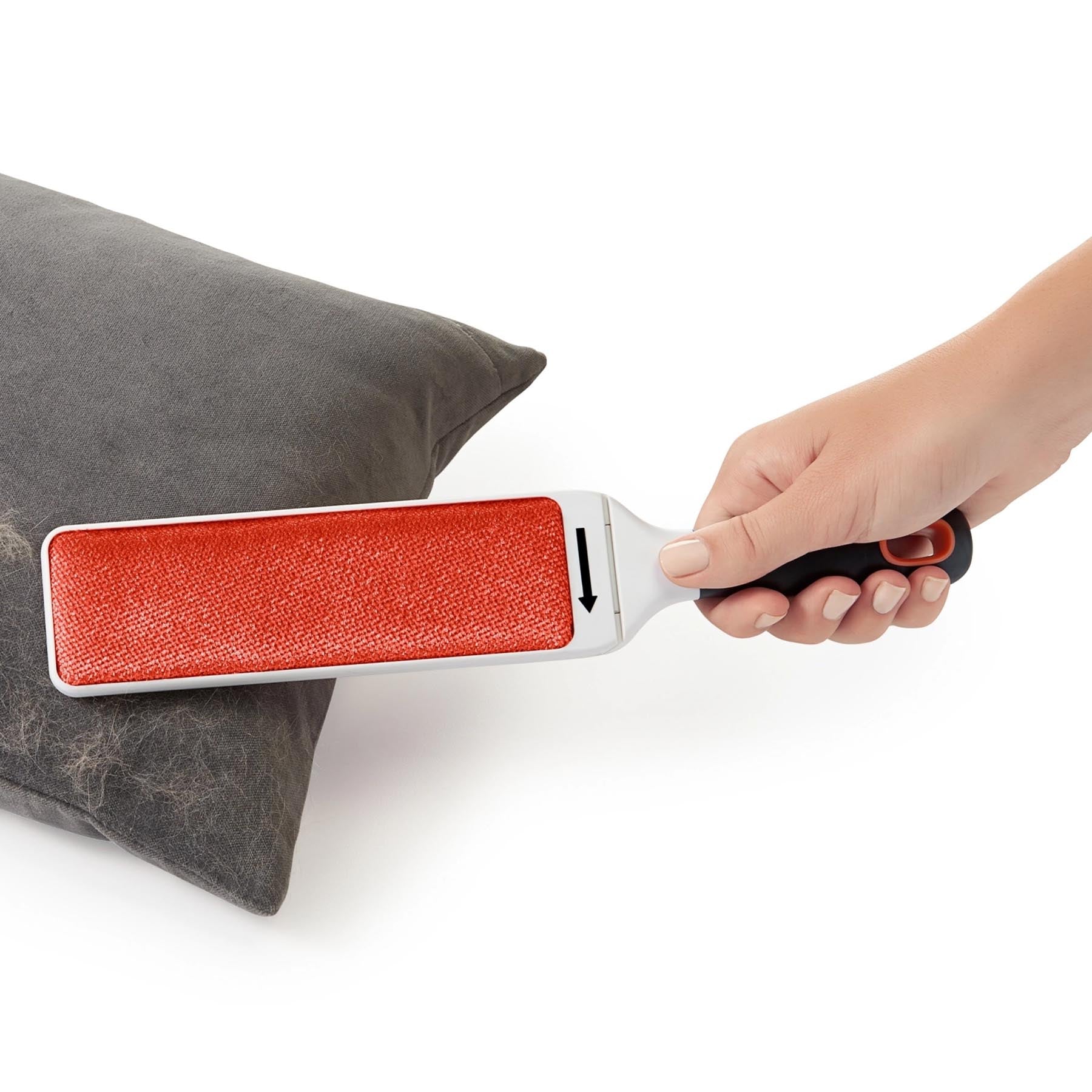 Flusenentferner Bürste in Weiß-Orange von OXO, ideal zur Reinigung von Möbeln. Praktisches Design für effektive Fusselentfernung.