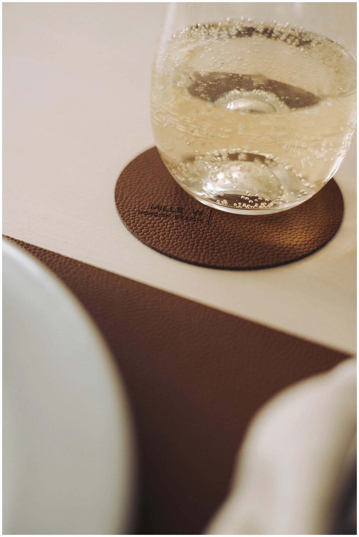 Runder Untersetzer in Cognac-Braun, Durchmesser 10 cm, Höhe 0.2 cm, als Pfannenuntersatz auf einer Tischoberfläche platziert.
