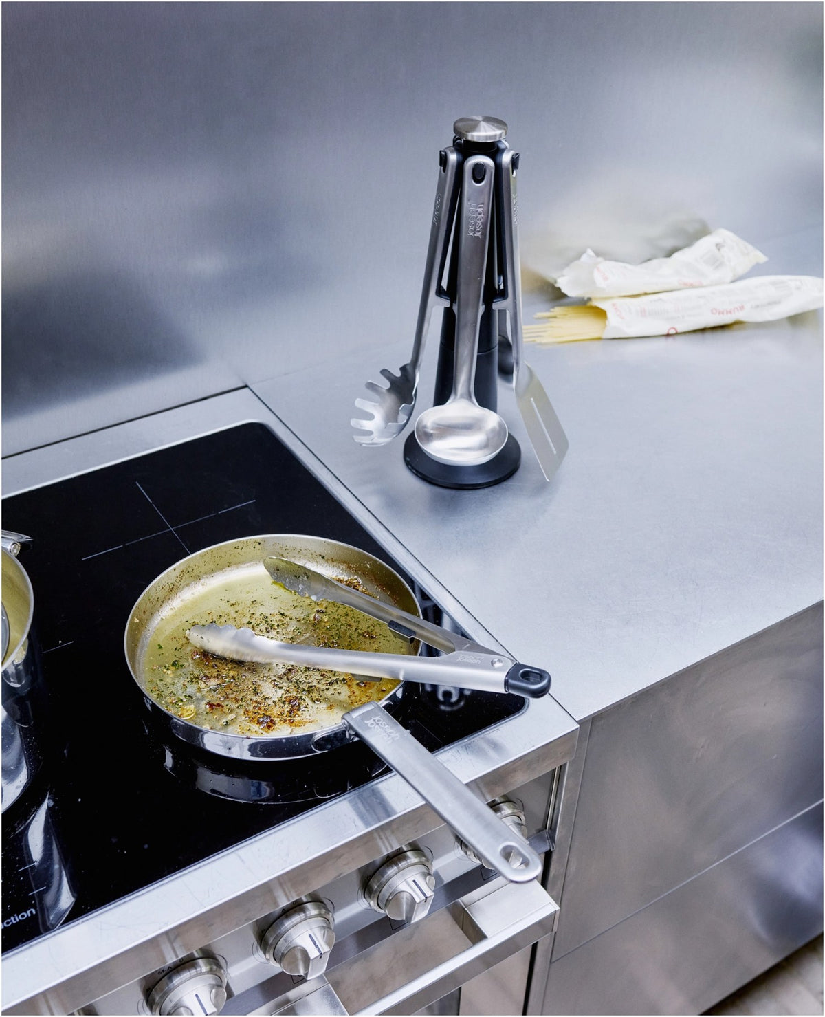 5-teiliges Utensilienhalter-Set aus Edelstahl in Silber: Kochlöffel, Schlitzwender, Spaghettizange, Schöpfkelle, Grillzange auf drehbarem Karussell.