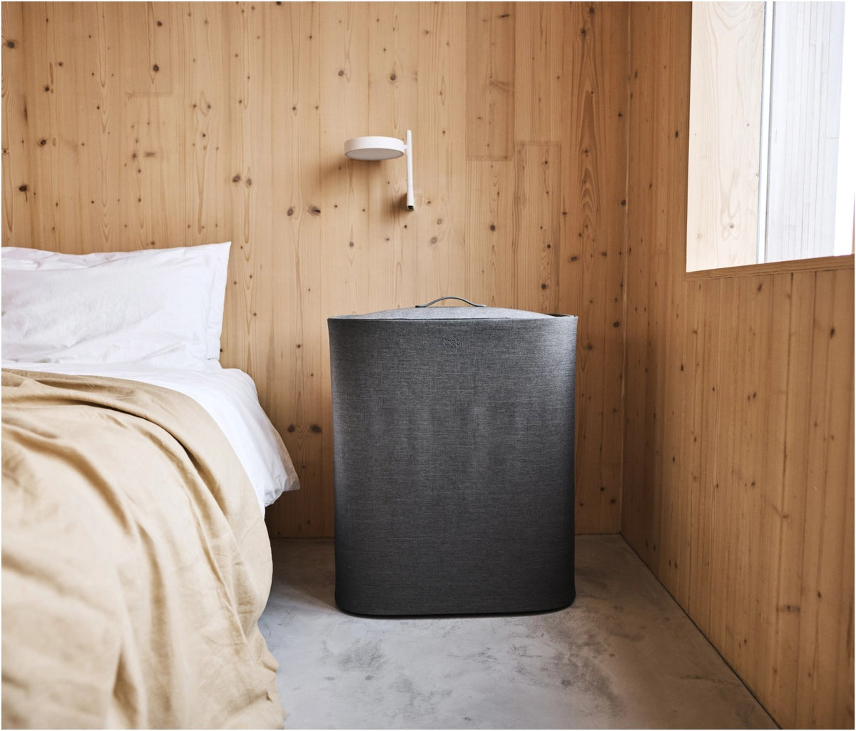 Grauer Wäschetrennkorb mit drei herausnehmbaren Stofftaschen à 30 Liter, Tragegriffen und Deckel mit Filzoberfläche, Frontalansicht.