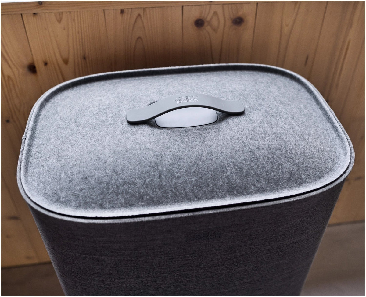 Grauer Wäschetrennkorb Tota One 60l von Joseph Joseph mit seitlichem Filzdeckel und herausnehmbarer Tragetasche für die Wäsche.
