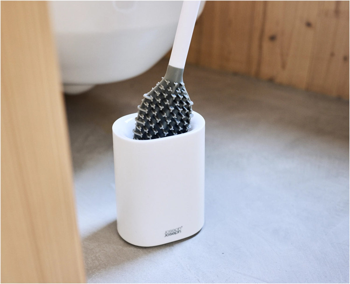 Weisse WC Bürste mit dreifach beklingten Borsten und passendem kompaktem Halter, glänzende Oberfläche, schlanke zylindrische Form.