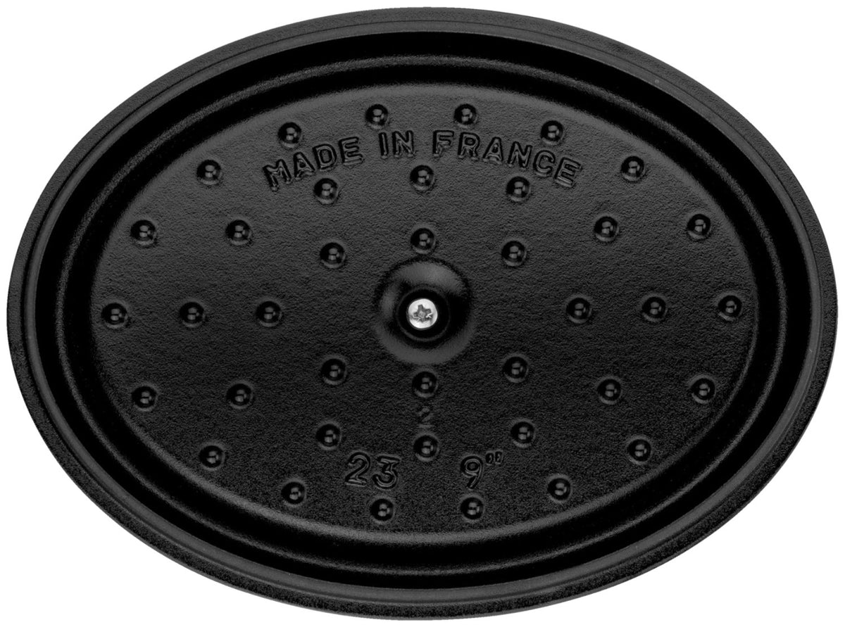 Ovale Staub Cocotte aus Gusseisen in brauner Emaille-Optik, 23 cm lang, mit Deckel und Tropfenstruktur auf der Innenseite.