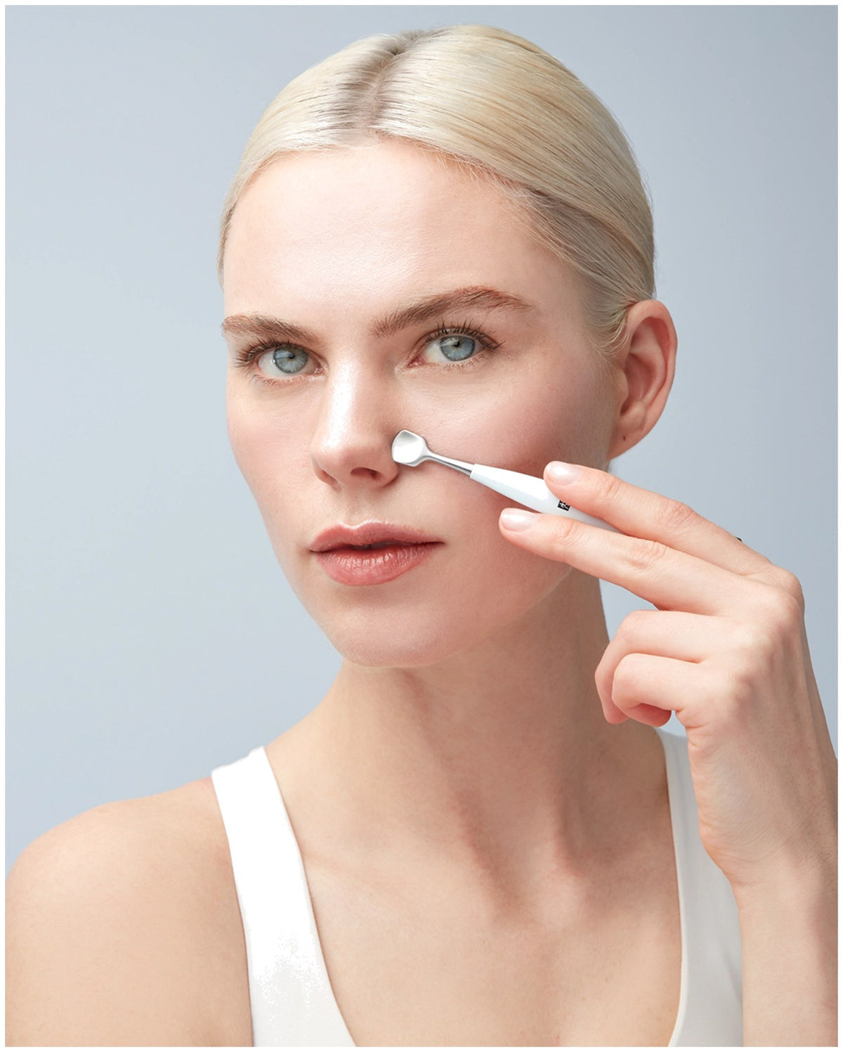 Silberfarbenes Facial Pore Refiner Tool aus Edelstahl mit zwei funktionalen Enden für die Gesichtspflege, liegend fotografiert.