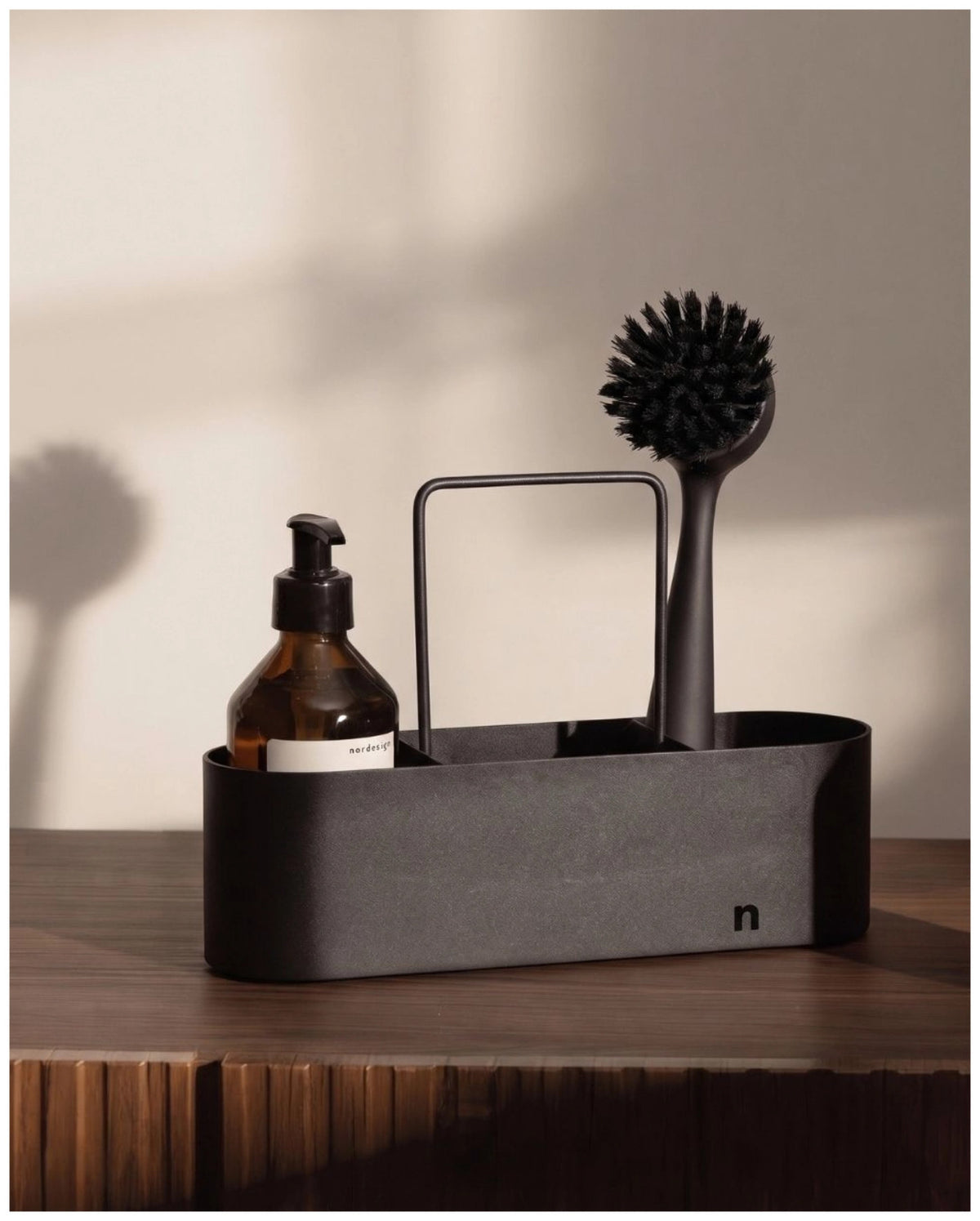 Schwarze Spülbürste aus Kunststoff von Nordesign mit schlankem Griff, wechselbarem Bürstenkopf und integriertem Magnet an der Unterseite.