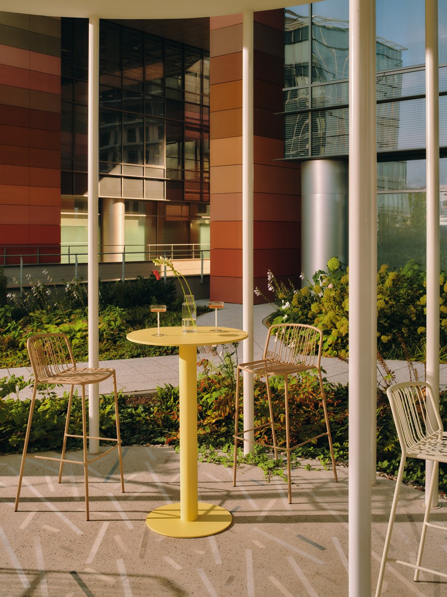 Zwei Barhocker mit durchbrochenem Sitz und Rückenlehne aus verzinktem Stahldraht, olivgrünes Gestell, schwarze Kunststofffüsse, Outdoor-Design.