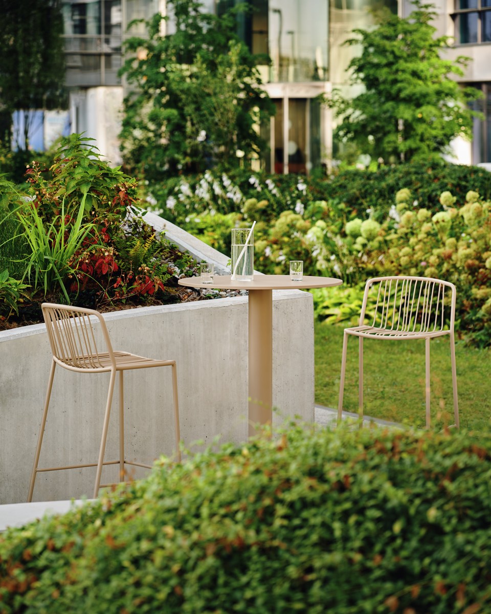 Zwei Barhocker mit durchbrochenem Sitz und Rückenlehne aus verzinktem Stahldraht, olivgrünes Gestell, schwarze Kunststofffüsse, Outdoor-Design.
