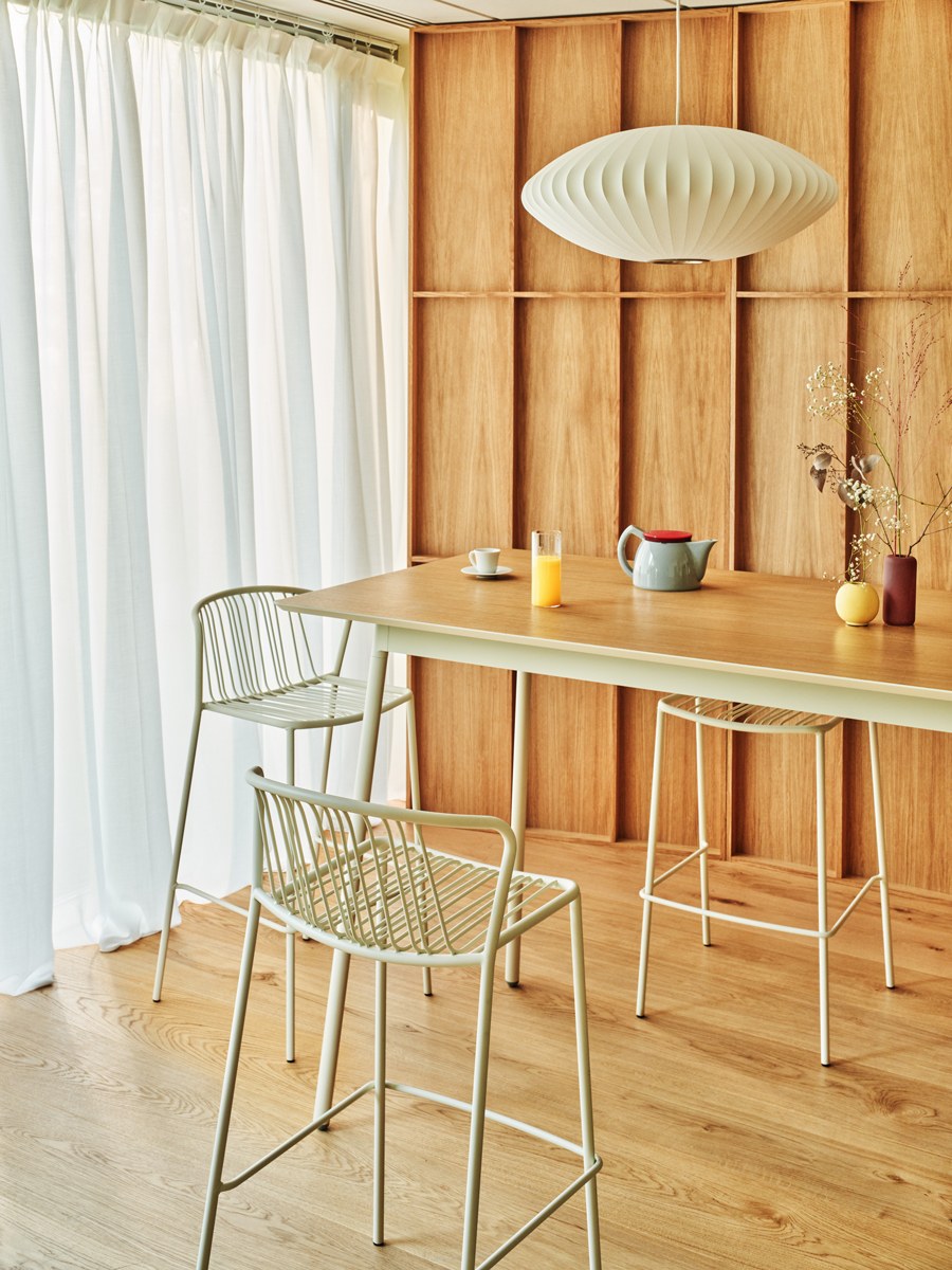 Zwei Barhocker mit durchbrochenem Sitz und Rückenlehne aus verzinktem Stahldraht, olivgrünes Gestell, schwarze Kunststofffüsse, Outdoor-Design.