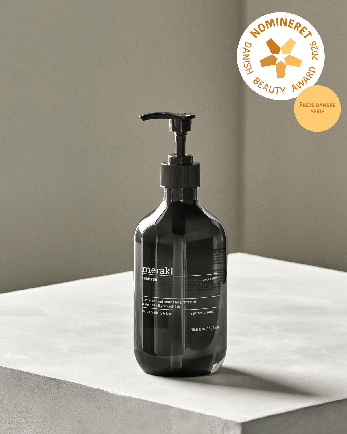 Flasche mit Meraki Deep Valley Shampoo, 490 ml, umgeben von natürlichen Elementen, die die sanfte Pflege für das Haar betonen.