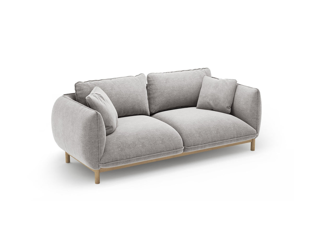Ada 2er Sofa von Micadoni in Mandel beige mit gepolstertem Velours-Bezug, geschwungener Rückenlehne und sichtbaren Buchenholzbeinen.