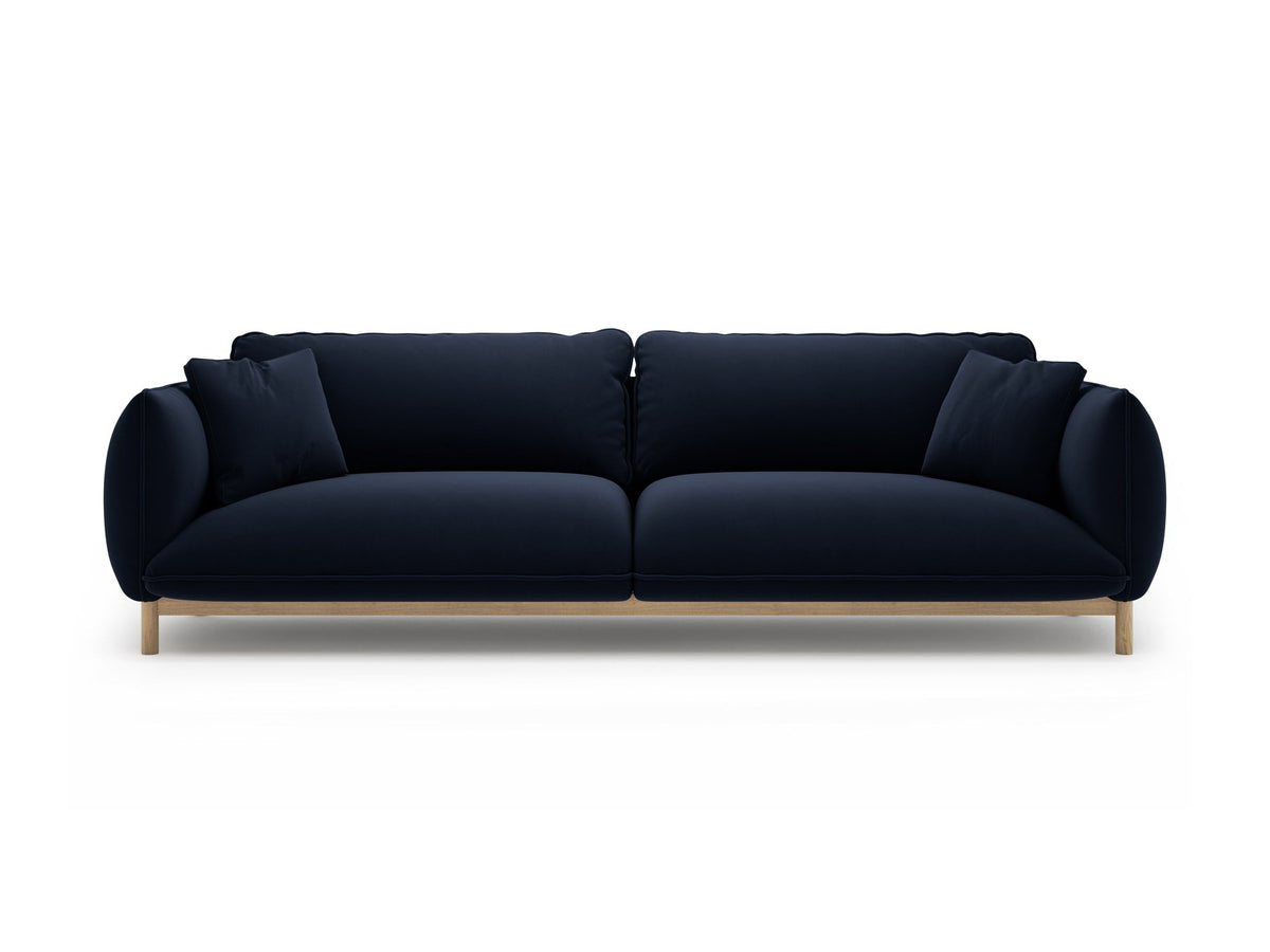 Vierersofa Ada von Micadoni in Mandel beige mit Casino-Stoffbezug, gerundeten Armlehnen und sichtbarem Buchenholzgestell auf Holzbeinen.
