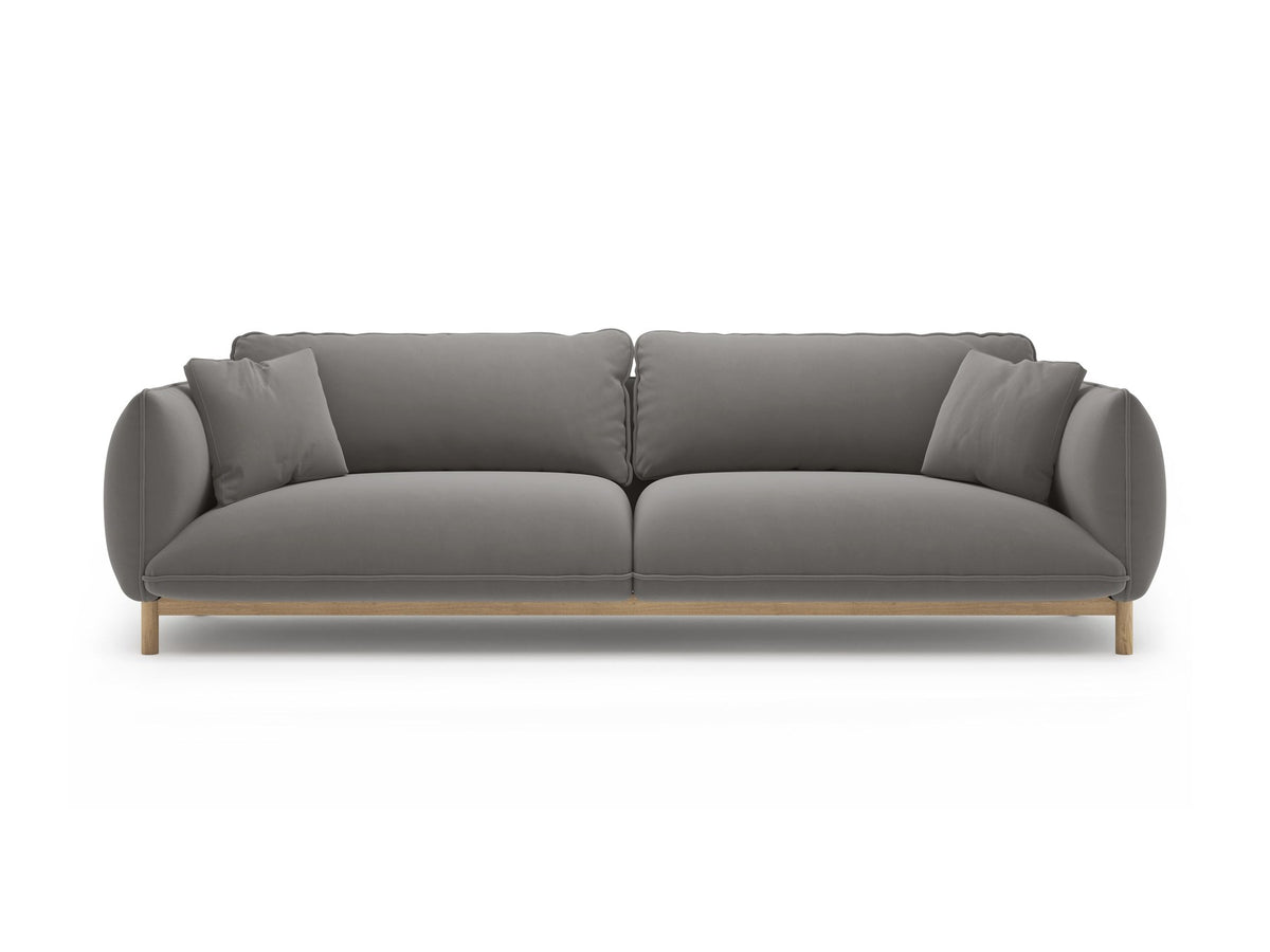 Vierersofa Ada von Micadoni in Mandel beige mit Casino-Stoffbezug, gerundeten Armlehnen und sichtbarem Buchenholzgestell auf Holzbeinen.
