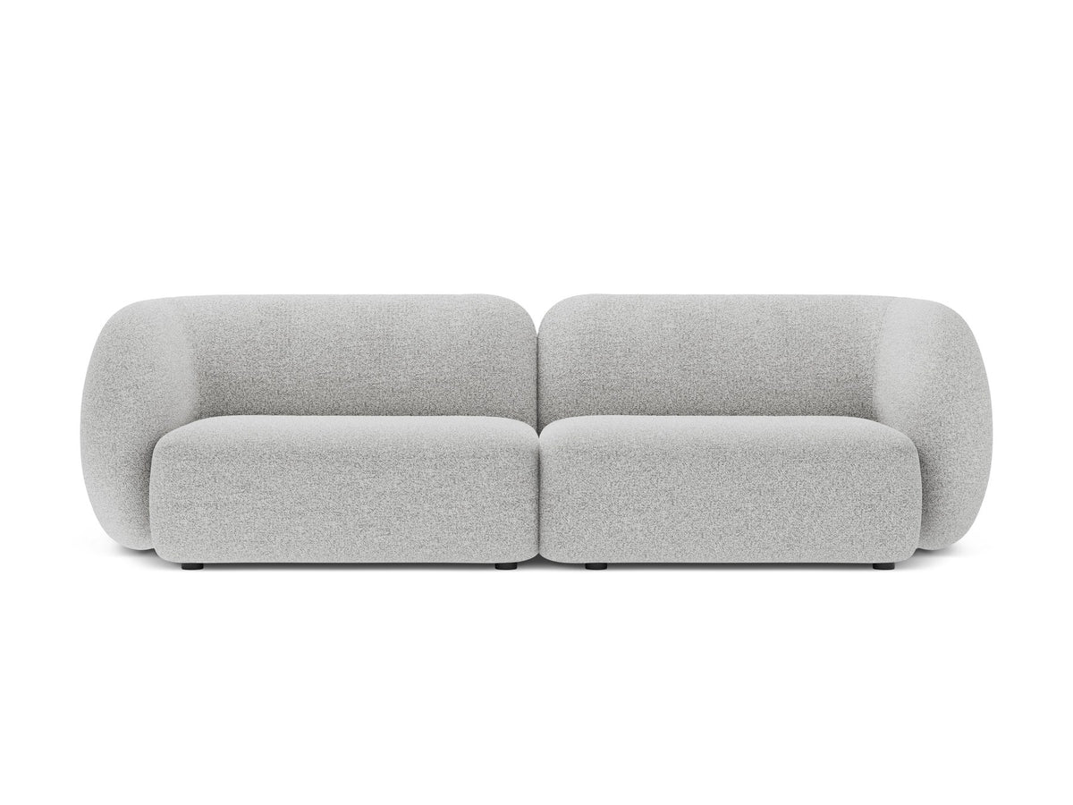 Weisses 4er Sofa Kate von Micadoni mit strukturiertem Bouclé-Stoff, schwarzen Kunststoffbeinen und breiter Sitzfläche.