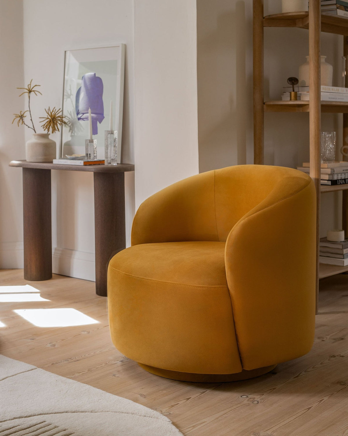 Drehbarer Sessel Letizia in leichtem Beige mit Chenille-Stoffbezug, gepolsterter Sitzfläche und niedrigen, stoffbezogenen Beinen.