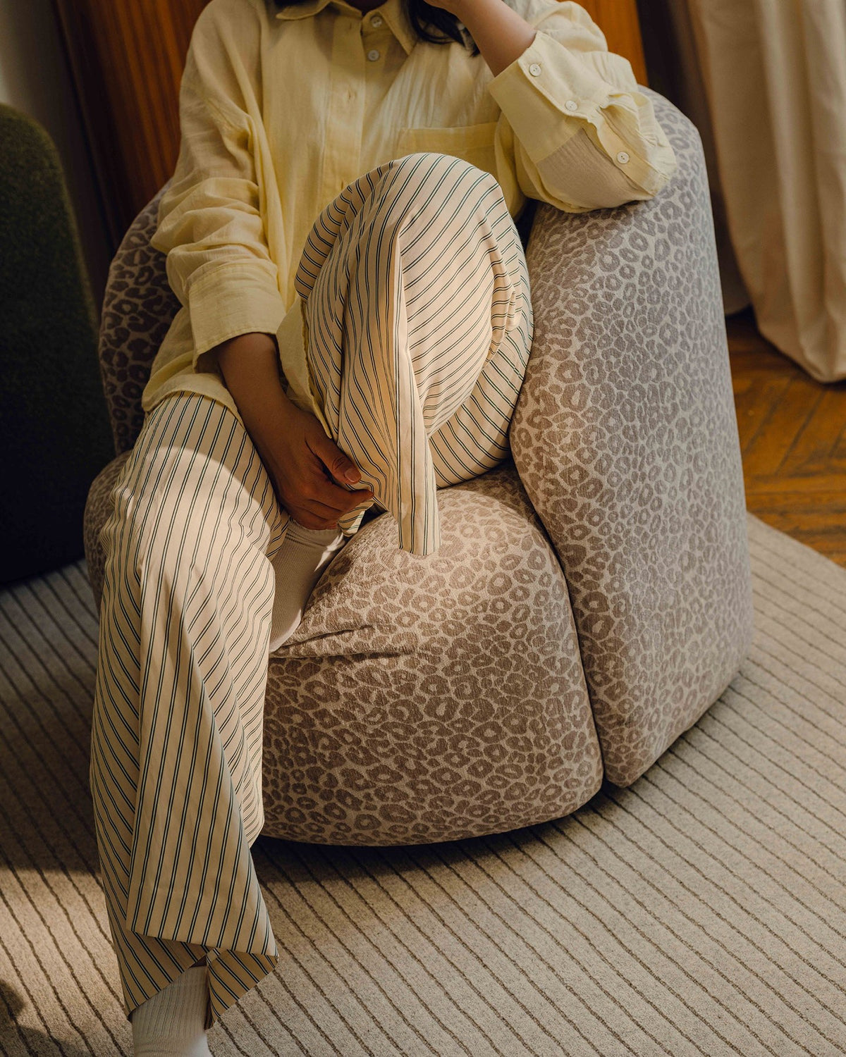 Drehbarer Sessel Letizia in leichtem Beige mit Chenille-Stoffbezug, gepolsterter Sitzfläche und niedrigen, stoffbezogenen Beinen.