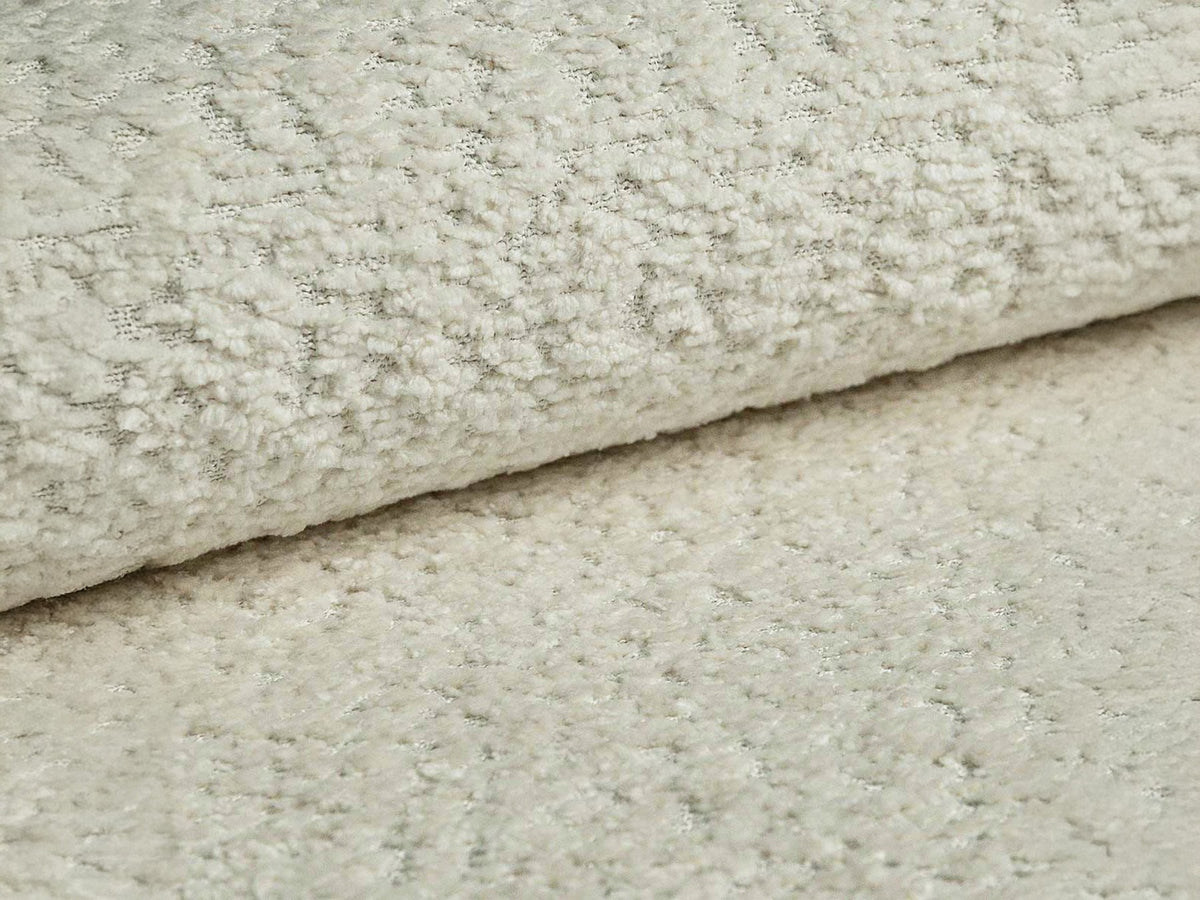 Beige Armsessel Abby von Micadoni mit strukturiertem Heritage-Stoffbezug, schwarzen Kunststoffbeinen und runder, kompakter Formgebung.