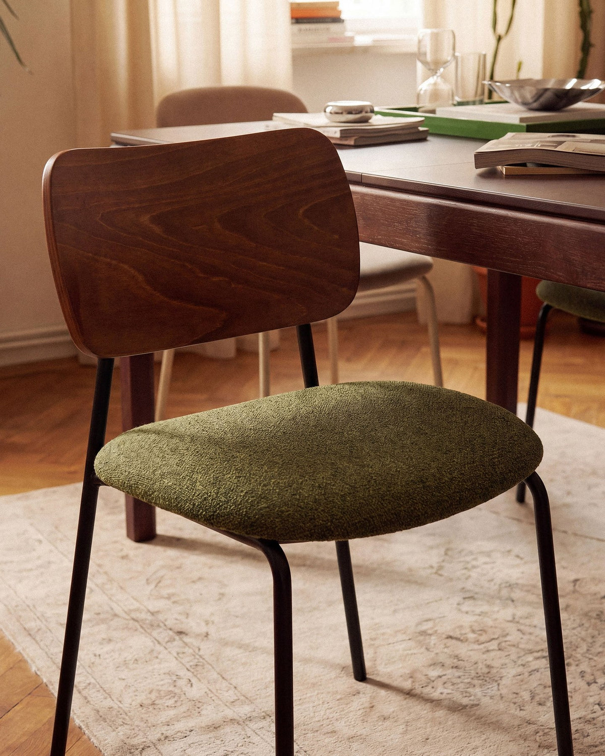 Beiger Samtstuhl mit gepolstertem Sitz aus Bouclé-Stoff, ergonomischer Rückenlehne aus Buchenholz und schwarzen Stahlbeinen im Esszimmer.