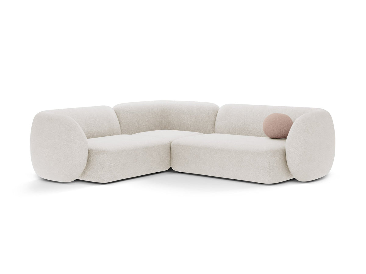 Weisses Ecksofa links Kate von Micadoni mit Bouclé-Stoff Baloo, schwarzen Kunststoffbeinen und niedriger Rückenlehne im Wohnraum.