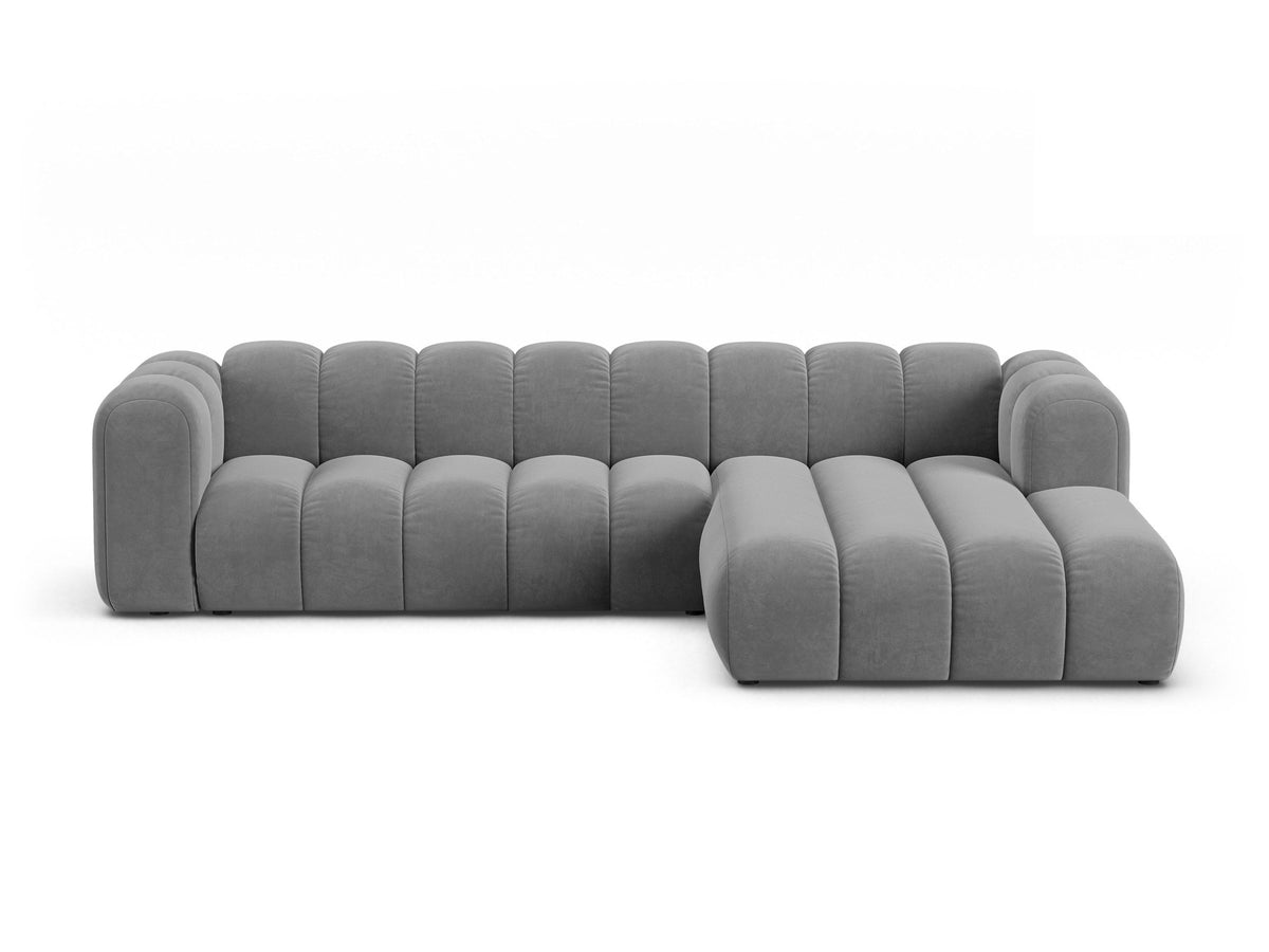 Linksseitig ausgerichtetes Ecksofa Lupine mit Samtbezug in leichtem Beige, schwarzen Kunststoffbeinen und tiefer Sitzfläche, Frontalansicht