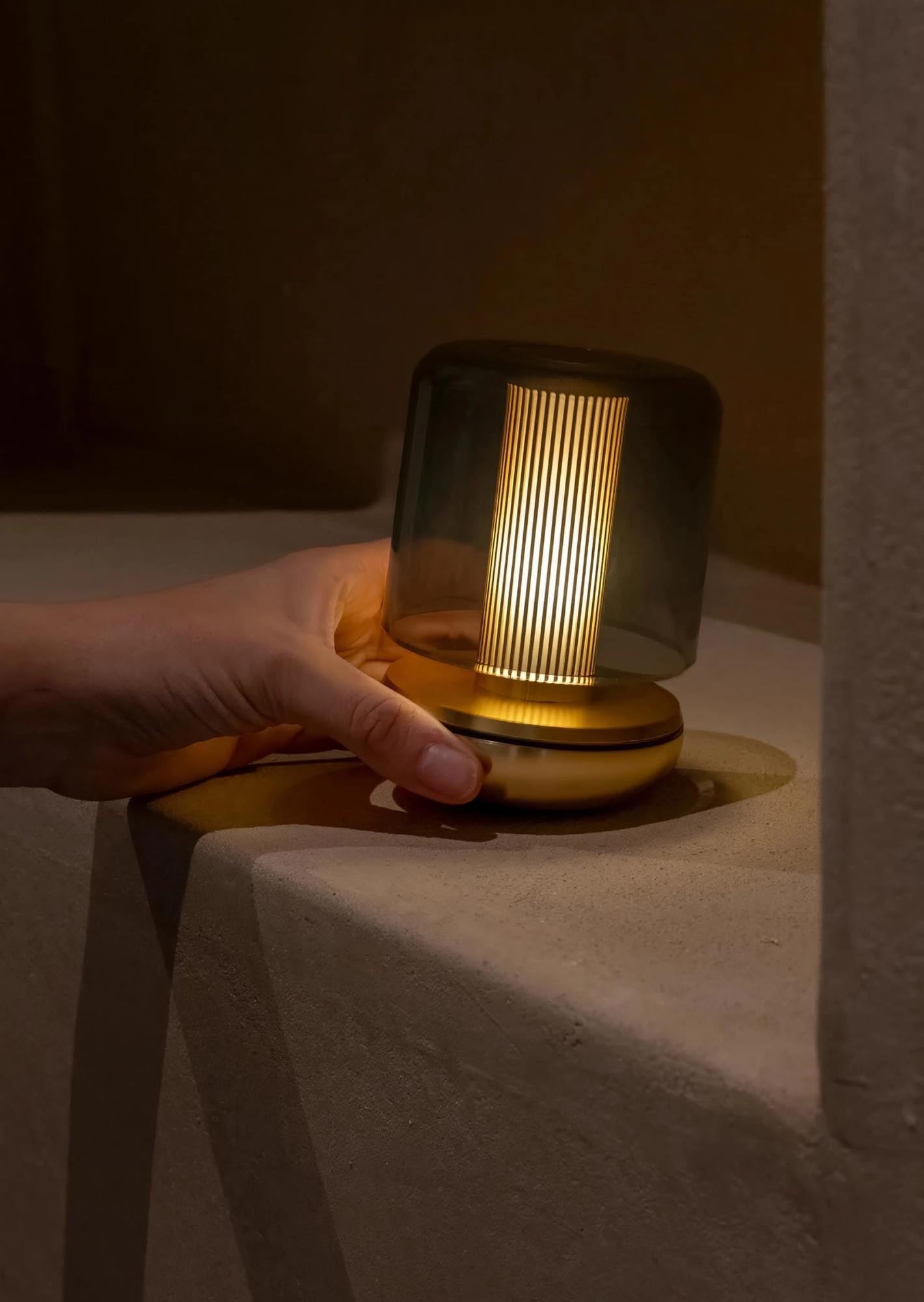 Die Firefly Tischlampe von Humble Light kombiniert smoked Glas mit goldenen Akzenten, 11.8x8.6cm, ideal für stilvolle Beleuchtung.