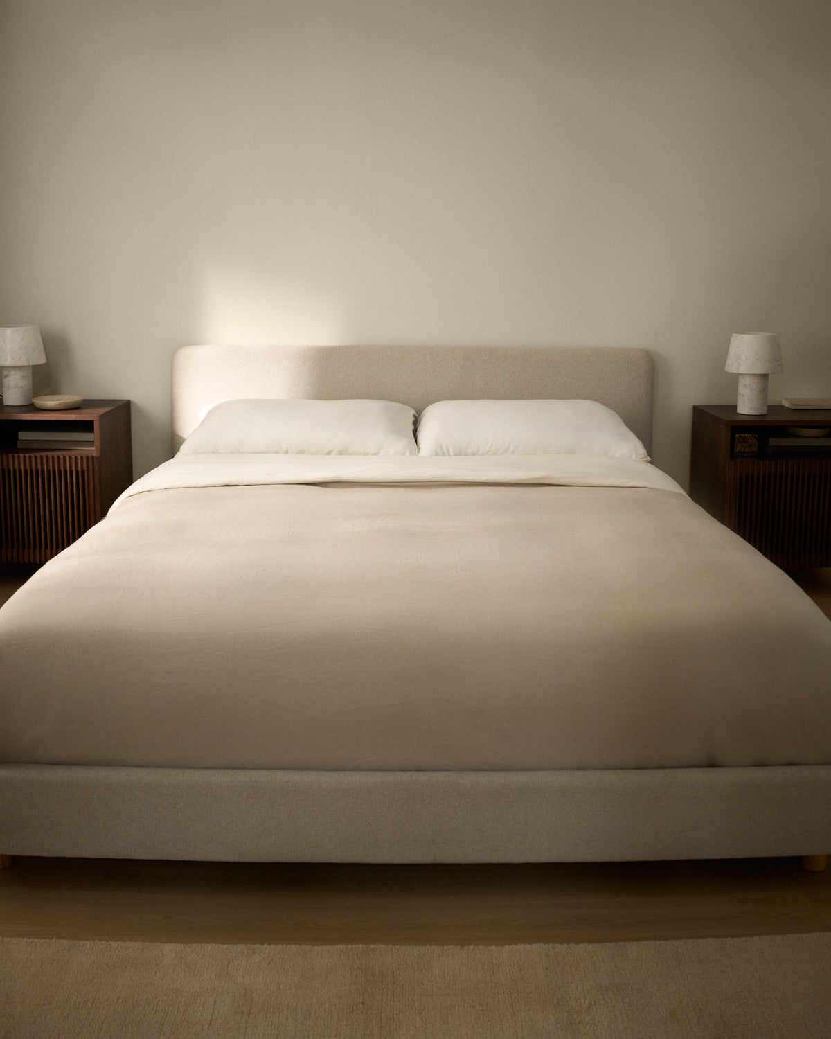 Polsterbett Selven von Kave Home in Beige mit geschwungenem Kopfteil, Chenille-Bezug, Gestell aus Holz und Eisen, Beine aus massivem Buchenholz