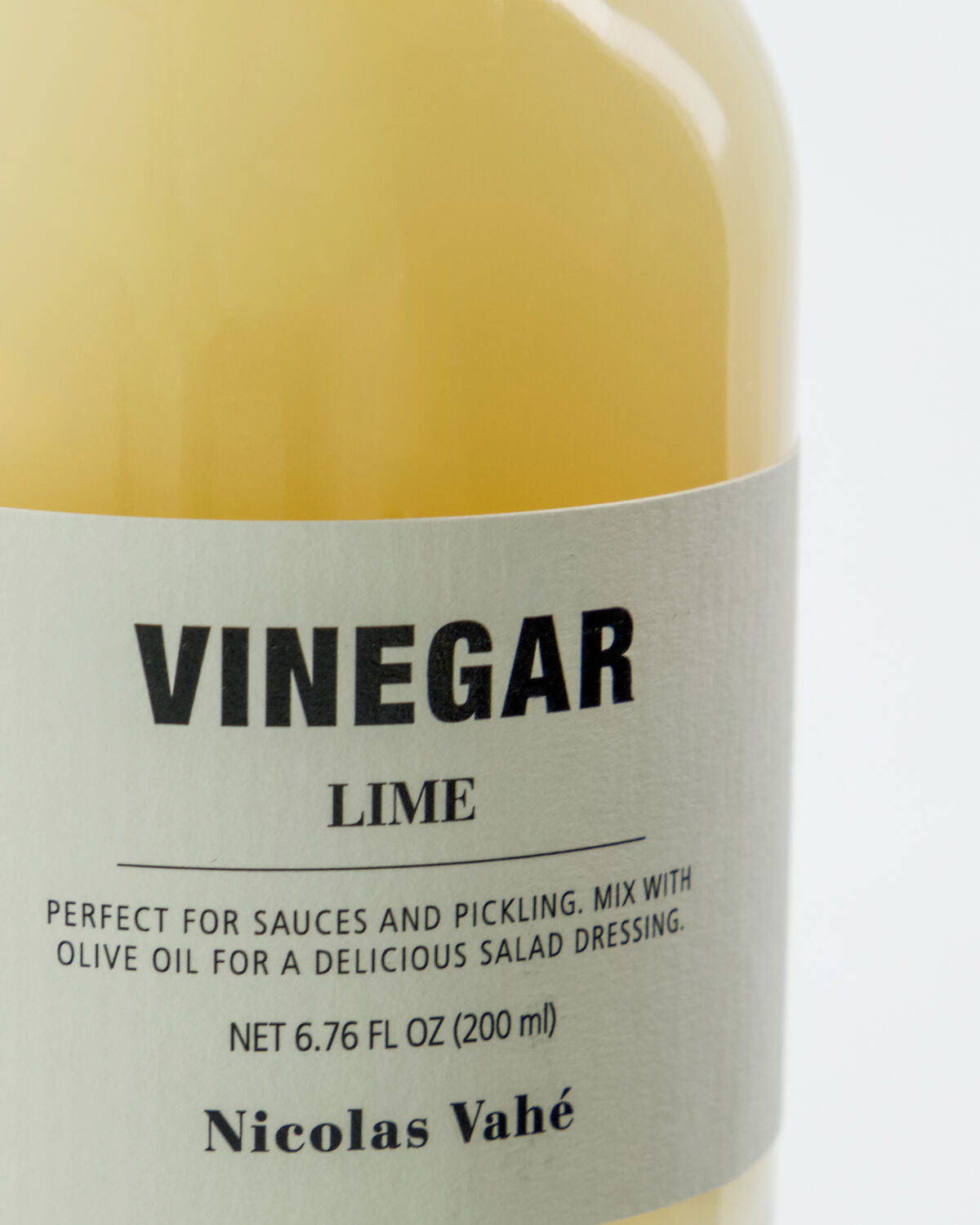 Elegante 200 ml Flasche Limettenessig von Nicolas Vahé, dekorativ auf Holz platziert, perfekt für feine Dressings und Marinaden.