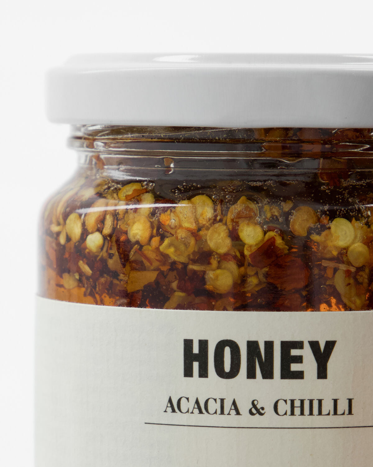 Ein elegantes Glas mit 250 g Honig, verfeinert mit Akazie und Chili, auf einem rustikalen Holzbrett arrangiert.