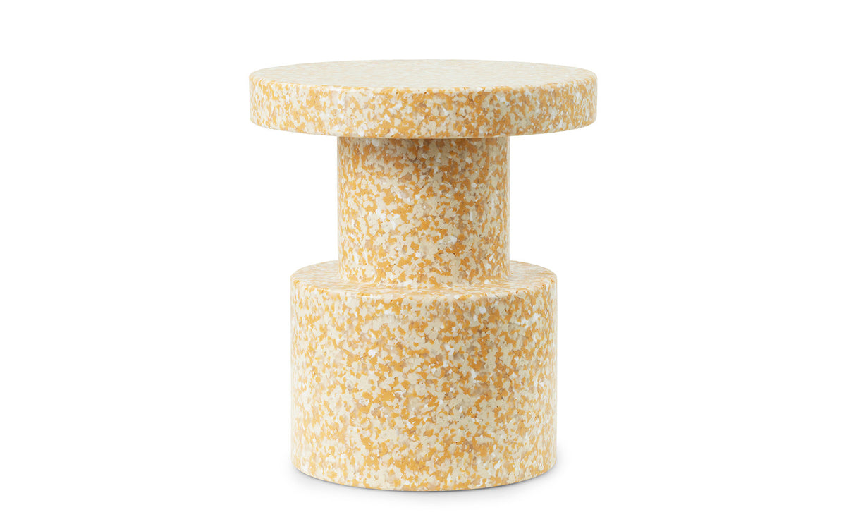 Runder Hocker mit zylindrischer Form in Senf, Oberfläche aus kleinen Partikeln von recyceltem Polyethylen, hergestellt im Rotationsformverfahren.