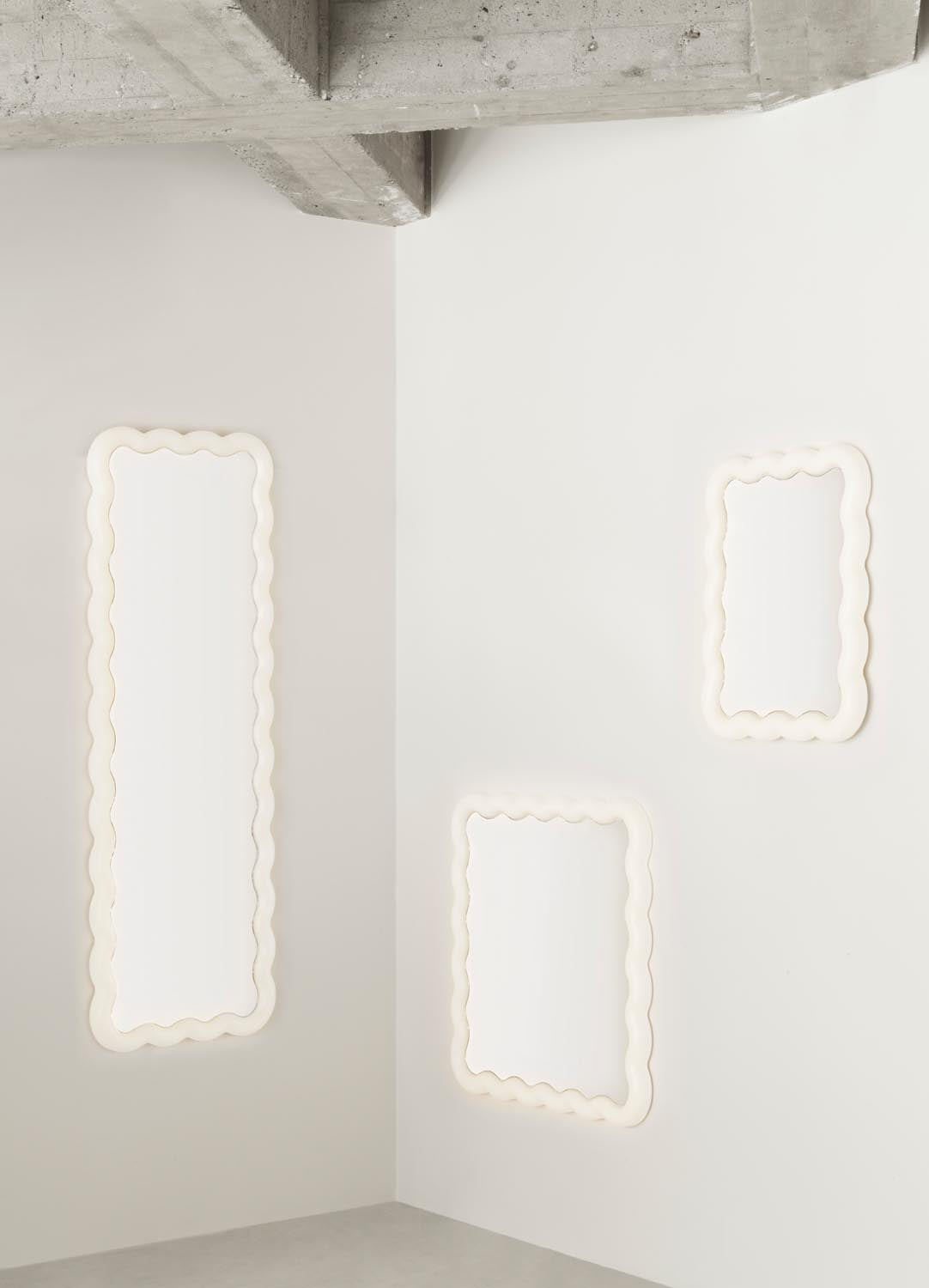 Quadratischer Spiegel Illu 80 x 80 cm von Normann Copenhagen mit wellenförmigem Rahmen und LED-Beleuchtung aus Glas, Acryl und Stahl.