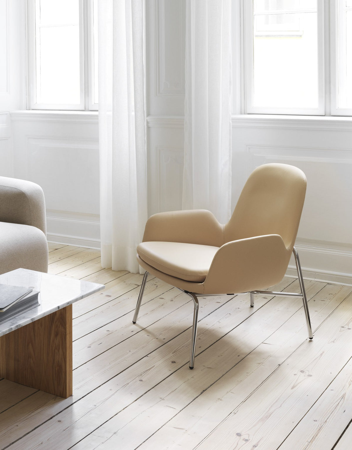 Era Lounge-Sessel von Normann Copenhagen in Beige mit gepolsterter Sitzschale, geschwungener Rückenlehne und schwarzem Stahlgestell.