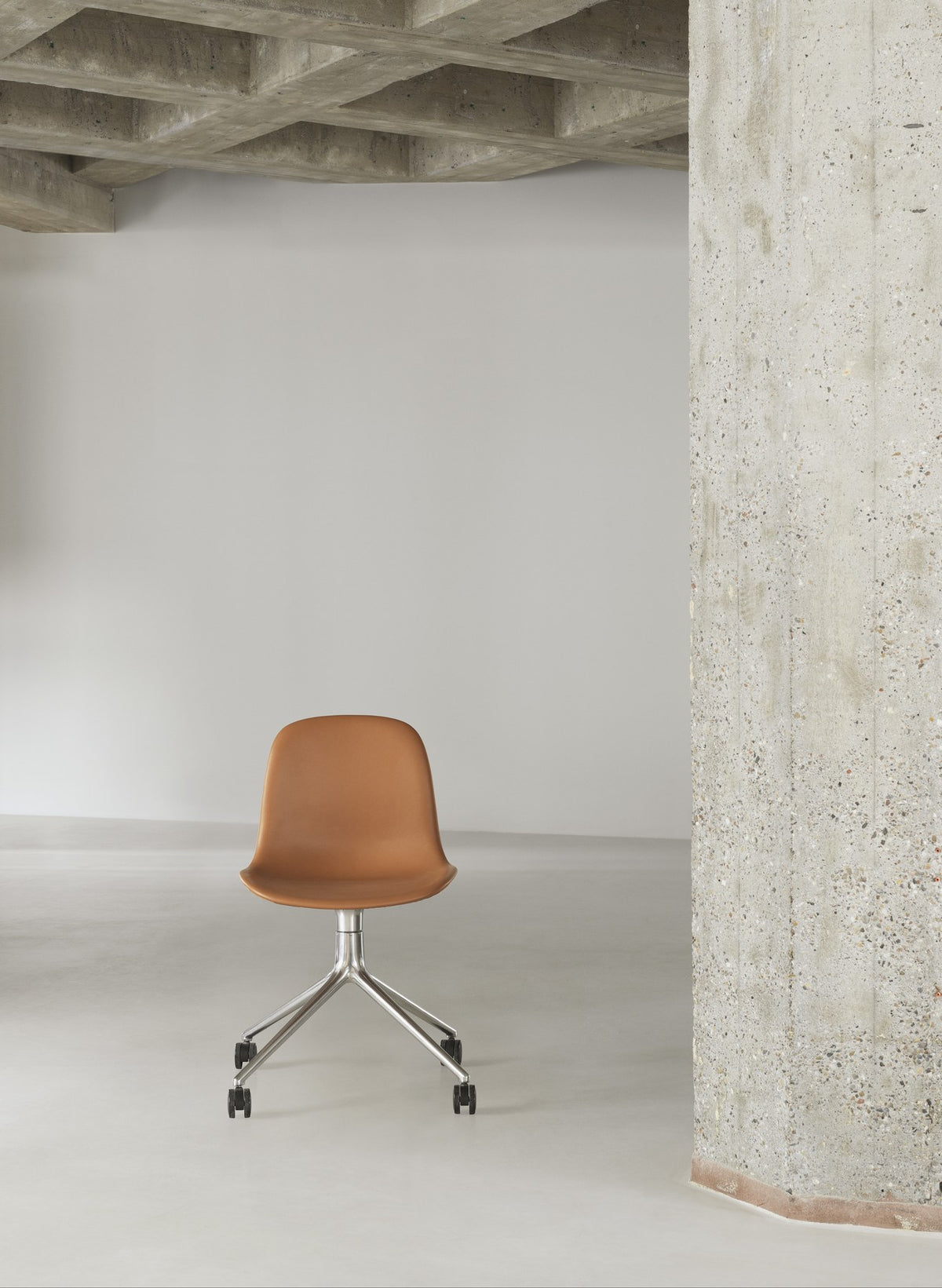 Form Drehstuhl von Normann Copenhagen mit gepolsterter Sitzschale in Braun und Drehgestell aus Aluminium mit vier Beinen.