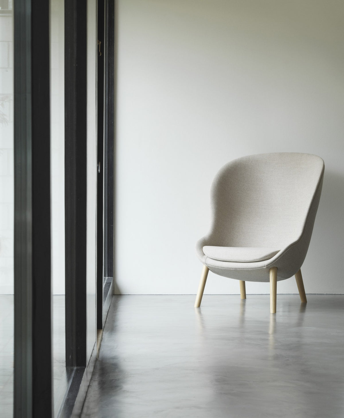 Hyg Lounge-Sessel Hoch von Normann Copenhagen in Beige mit Beinen aus schwarzer Eiche, hohe geschwungene Rückenlehne, PU-Schaum-Sitzschale.