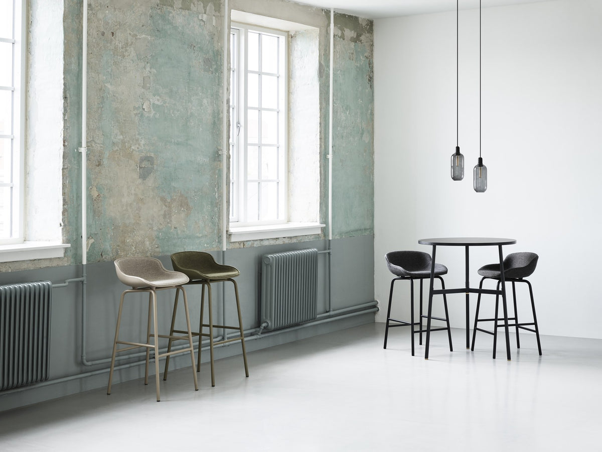 Barhocker Hyg von Normann Copenhagen mit grauer Sitzschale aus Polypropylen, gepolsterter Vorderseite und Gestell aus Stahl.