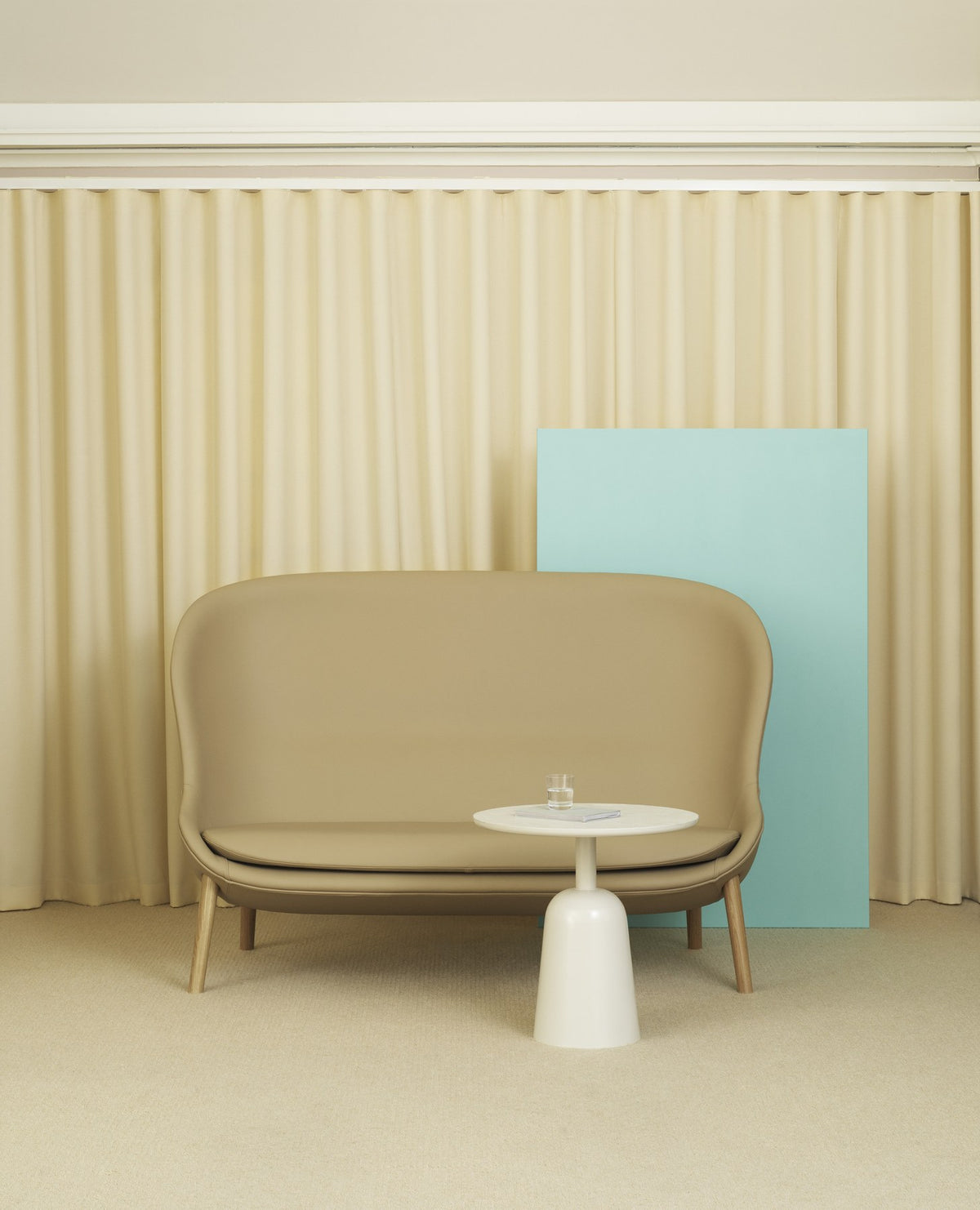 Hyg 2er Sofa von Normann Copenhagen in Beige mit Beinen aus schwarzer Eiche, geschwungene Form mit hohen Seitenteilen und breiter Sitzfläche.