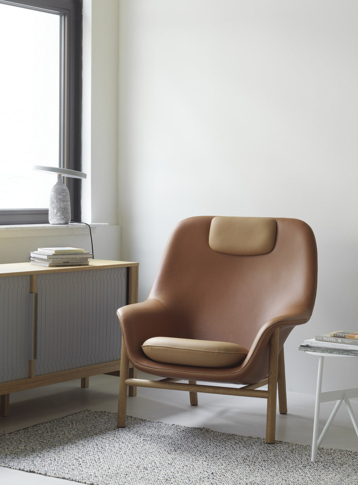 Drape Lounge-Sessel mit Kopfstütze von Normann Copenhagen in Cognac, geformte Sitzschale mit Holz- oder Stahlbeinen, Paspel-Detail.