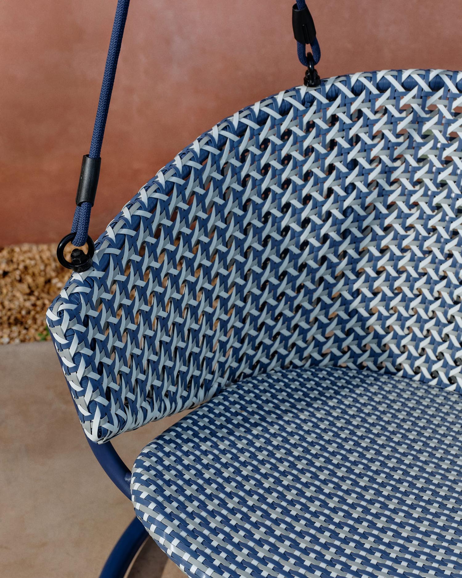 Eleganter Hängesessel aus Aluminium und blauem Rattan, robust, pflegeleicht, mit Fußteil für maximalen Komfort.